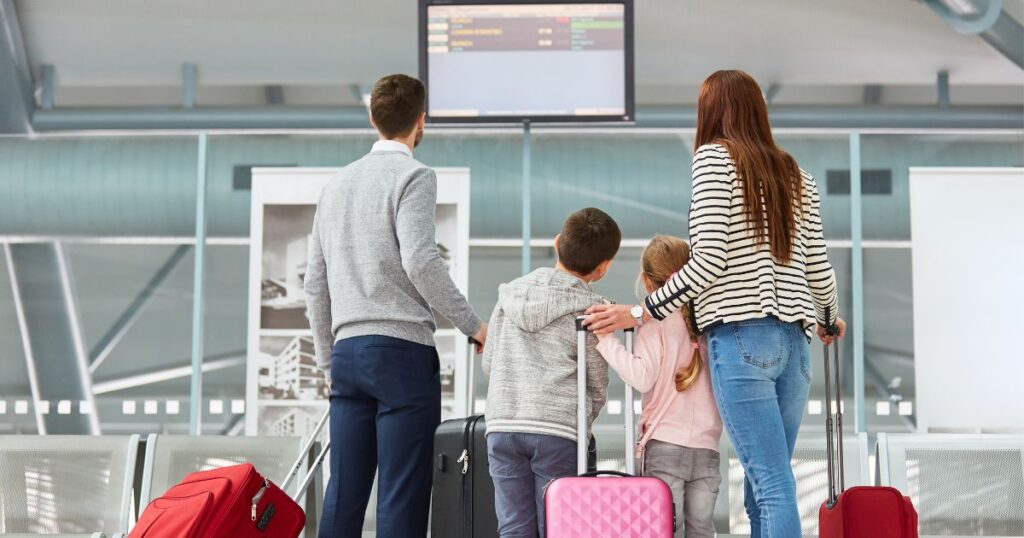 Family traveling at the airport with holiday travel insurance coverage checking for flight delays.