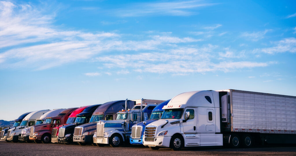 Row of semi trucks parked at a trucking yard, representing commercial vehicles for trucking insurance coverage.