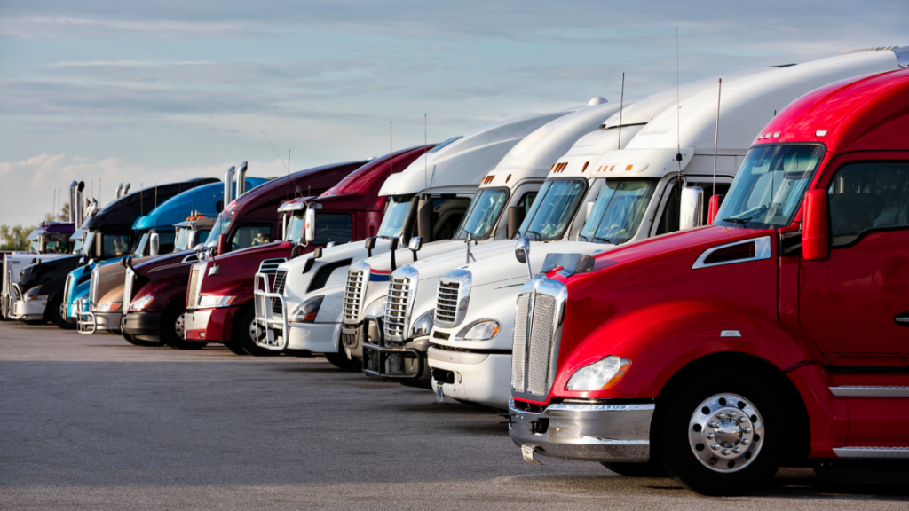 Row of multiple different colored big rigs in a lot.